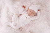 newborn baby in white outfit with hat